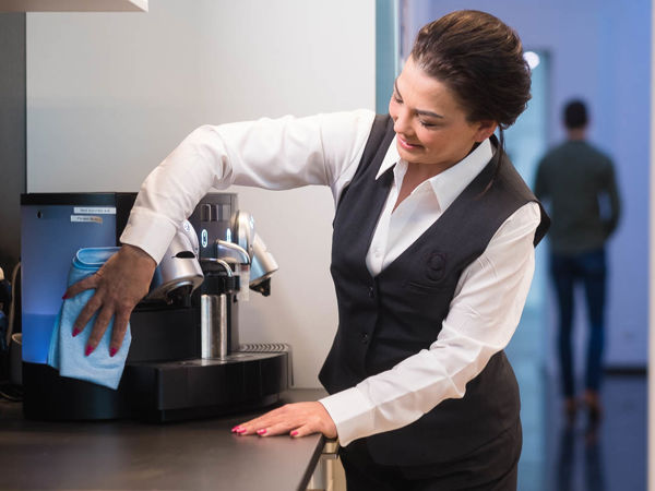Schoonmaakmedewerker die het koffiezetapparaat aan het schoonmaken is in de keuken