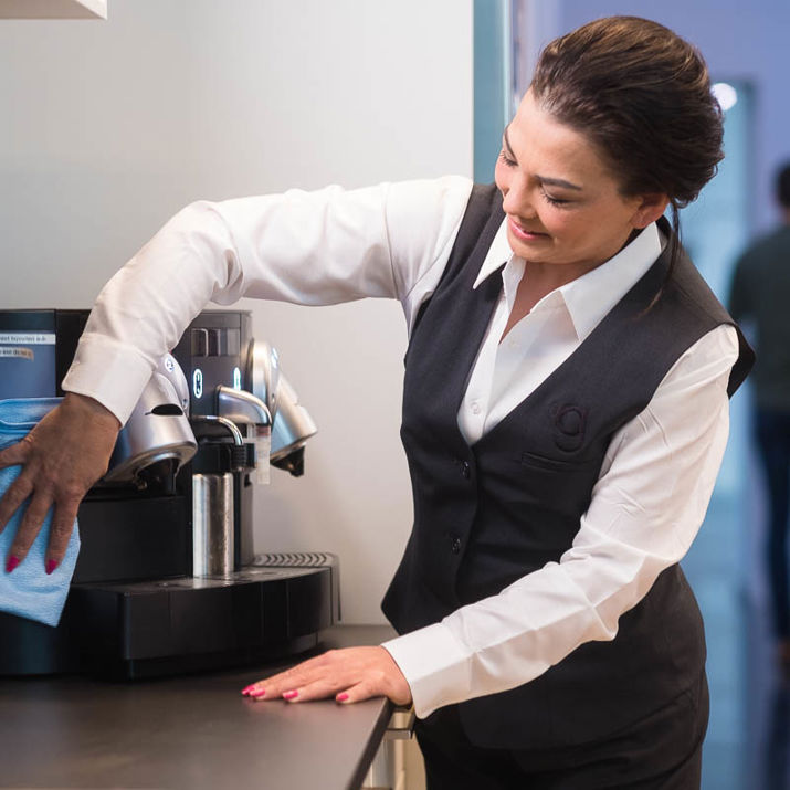 Schoonmaakmedewerker die het koffiezetapparaat aan het schoonmaken is in de keuken