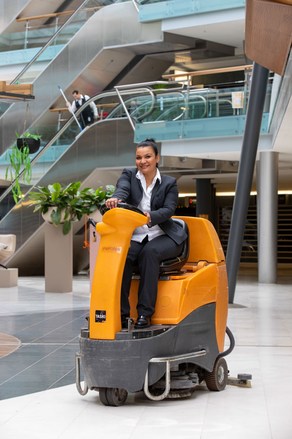 Schoonmaakmedewerker die de vloer aan het schoonmaken is op een schrobmachine