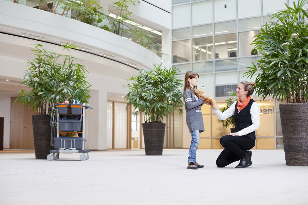 Schoonmaakmedewerker die een knuffel geeft aan een kind in een zorginstelling