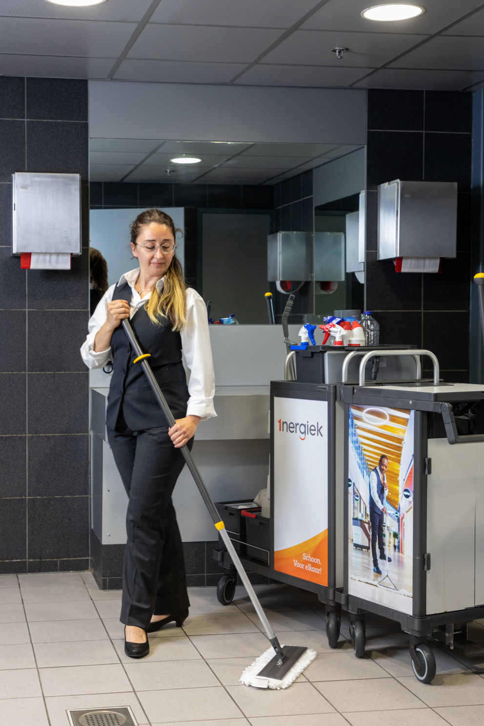 Schoonmaakmedewerker aan het dweilen in een sanitaire ruimte