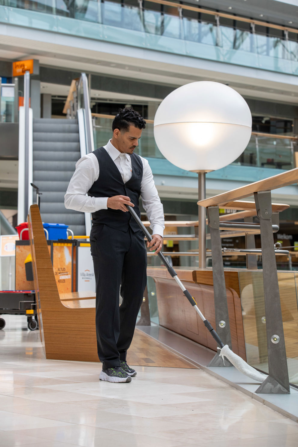 Schoonmaakmedewerker die de vloer aan het vegen is in een bedrijfspand