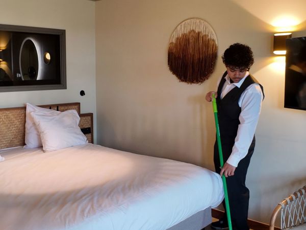 Schoonmaakmedewerker die de vloer aan het vegen is in een hotelkamer