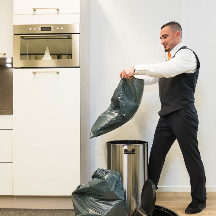 Schoonmaakmedewerker die de prullenbak verschoond in een keuken