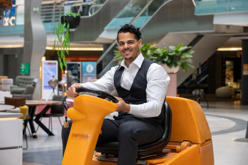 Schoonmaakmedewerker die vloeren aan het schoonmaken is op een schrobmachine