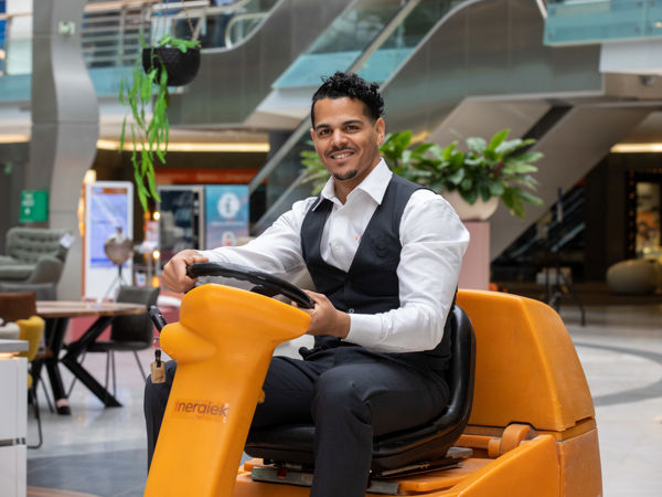 Schoonmaakmedewerker die vloeren aan het schoonmaken is op een schrobmachine