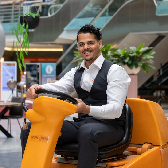 Schoonmaakmedewerker die vloeren aan het schoonmaken is op een schrobmachine