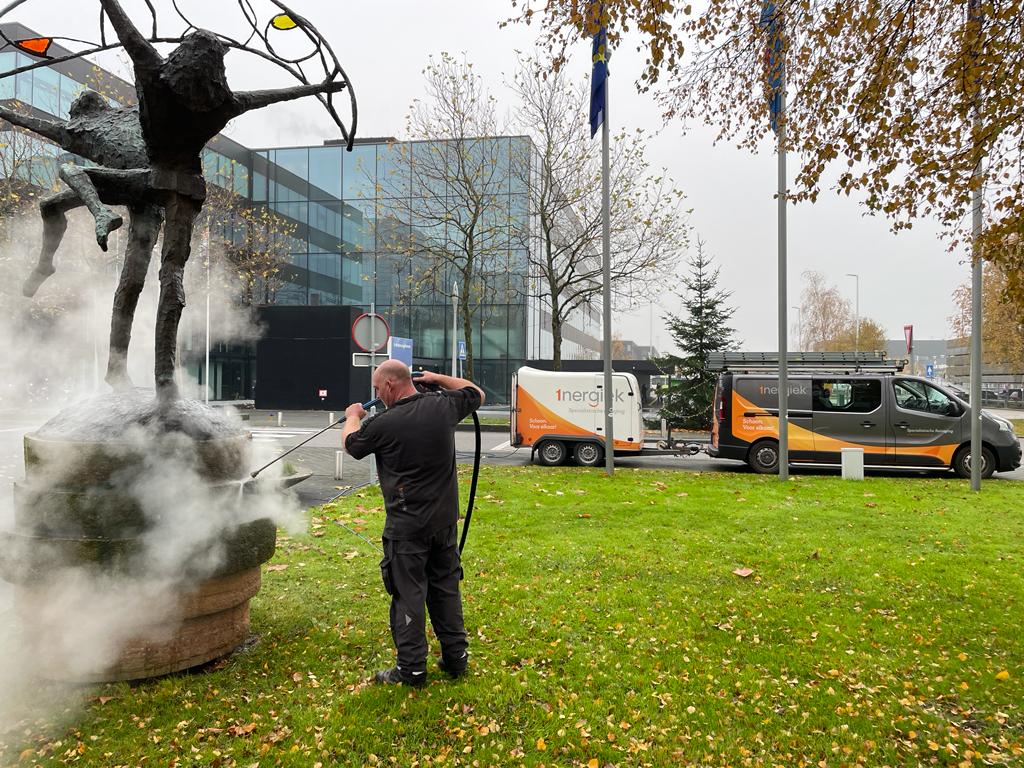 Medewerker specialistische reiniging die een beeld schoon spuit