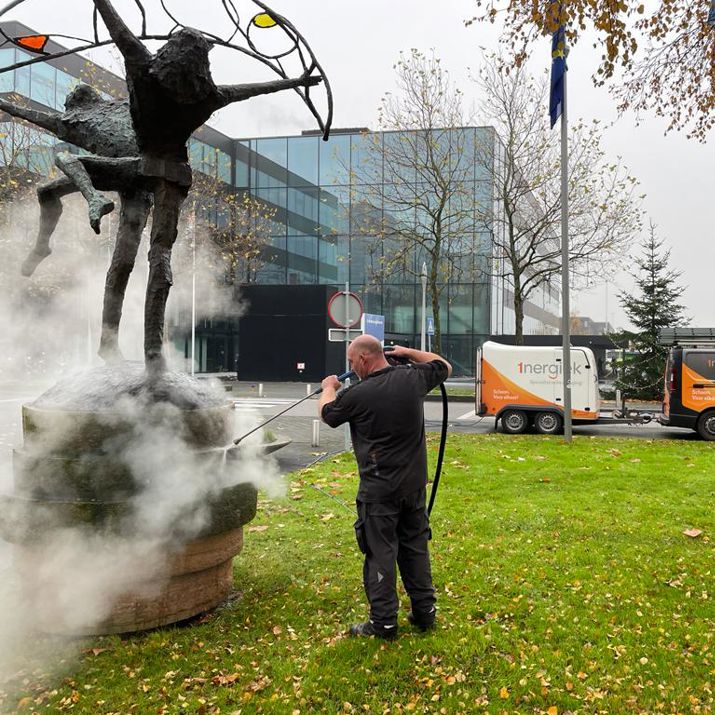 Medewerker specialistische reiniging die een beeld schoon spuit