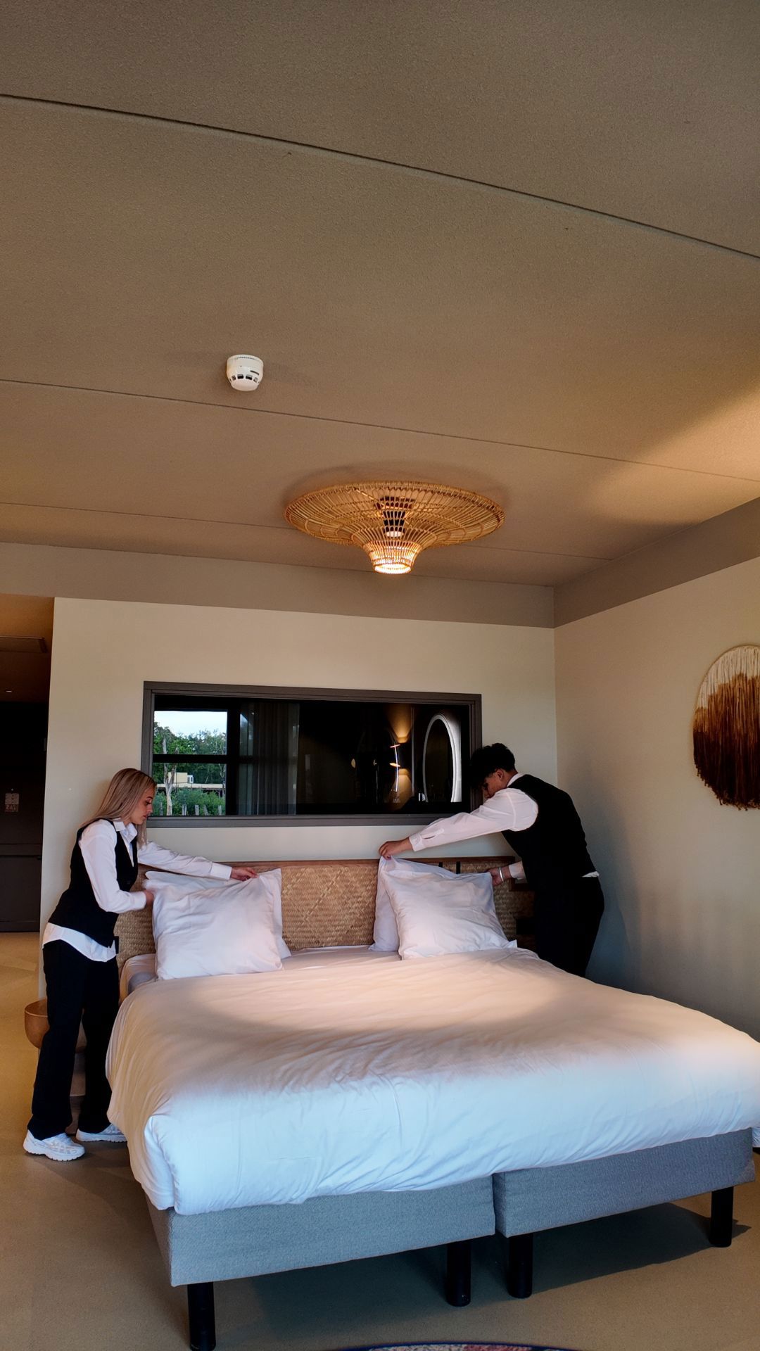 Schoonmaakmedewerkers die een bed opmaken in een hotelkamer