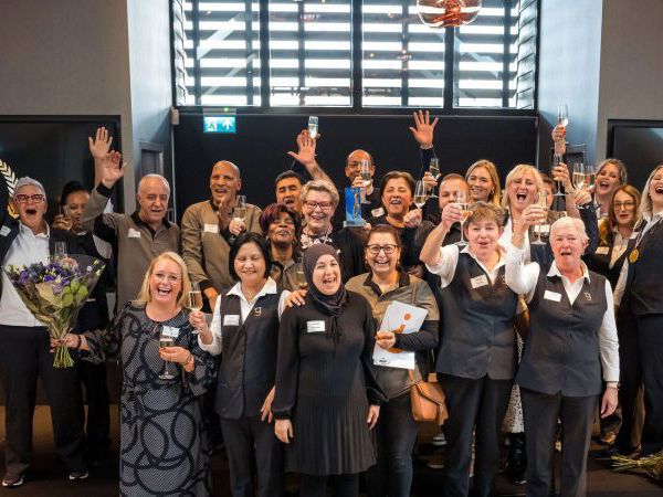 Groepsfoto van collega's van schoonmaakbedrijf die juichen