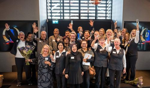 Groepsfoto van collega's van schoonmaakbedrijf die juichen