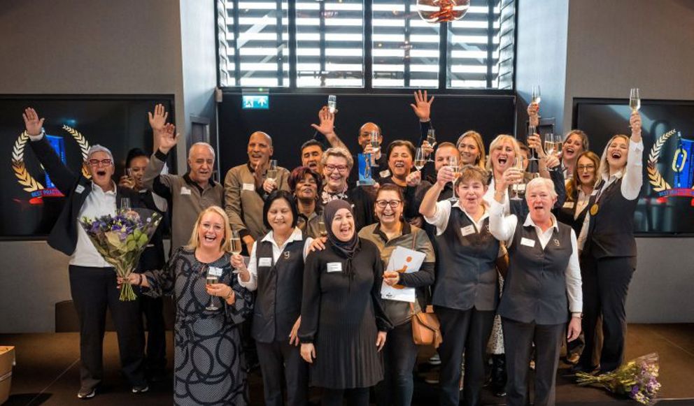 Groepsfoto van collega's van schoonmaakbedrijf die juichen