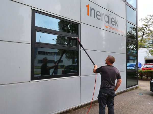 Glazenwasser die de ramen lapt van een bedrijfspand