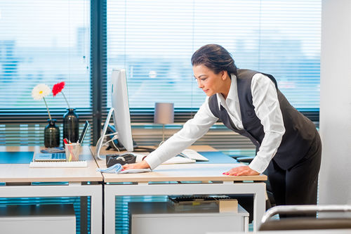 Schoonmaakmedewerker die een bureau schoonmaakt in een kantoorpand