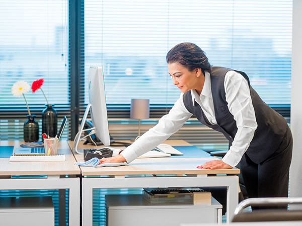 Schoonmaakmedewerker die een bureau schoonmaakt in een kantoorpand
