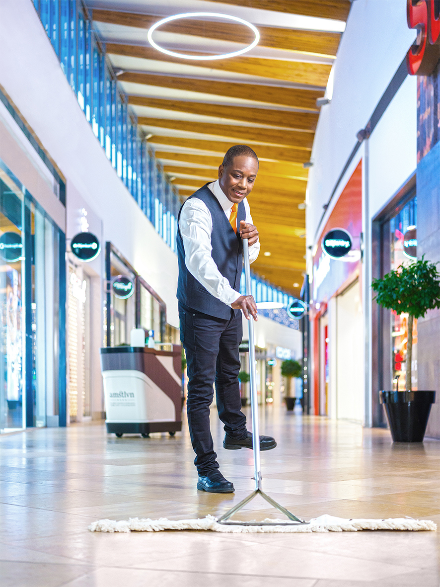 Schoonmaakmedewerker die vloeren aan het dweilen is in een winkelcentrum