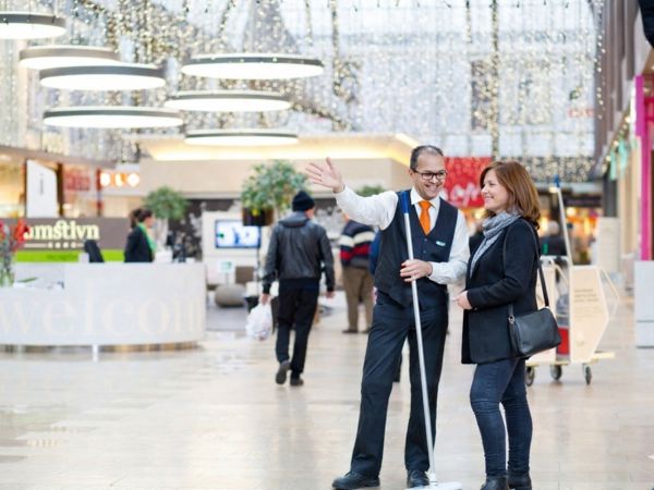 Facilitaire medewerker die een bezoeker in een winkelcentrum helpt