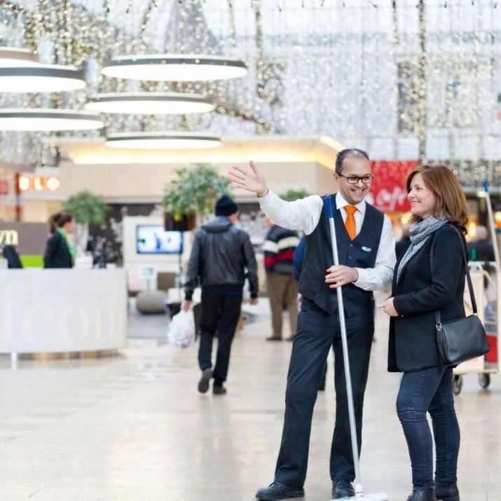 Facilitaire medewerker die een bezoeker in een winkelcentrum helpt